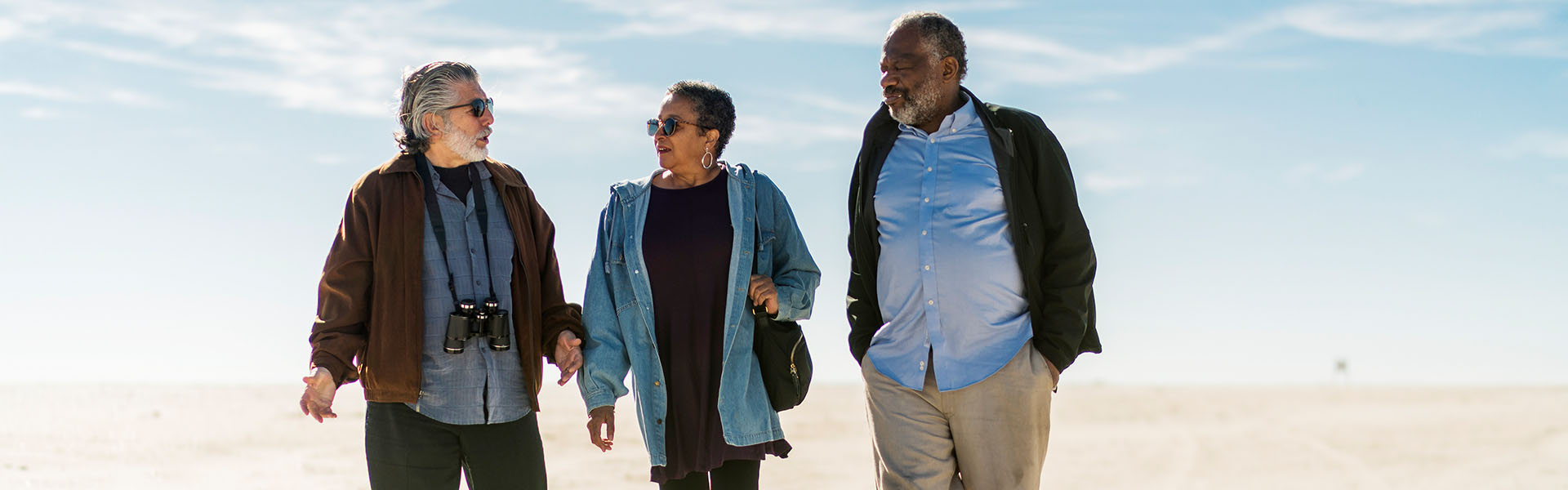 Two older men and woman walking and talking together