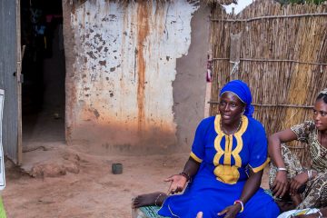 Woman holds a chart about family planning while talking to people outside their home