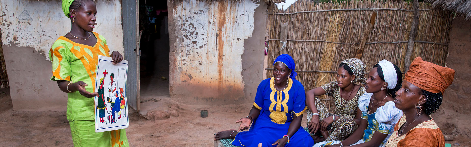 Woman holds a chart about family planning while talking to people outside their home