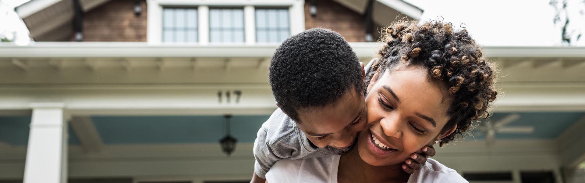 Single mother playing with young sons in front of house