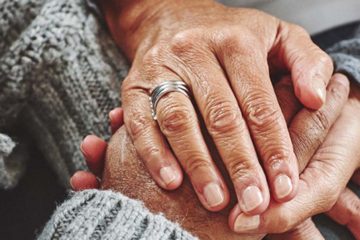 Female carer holding hands of senior man