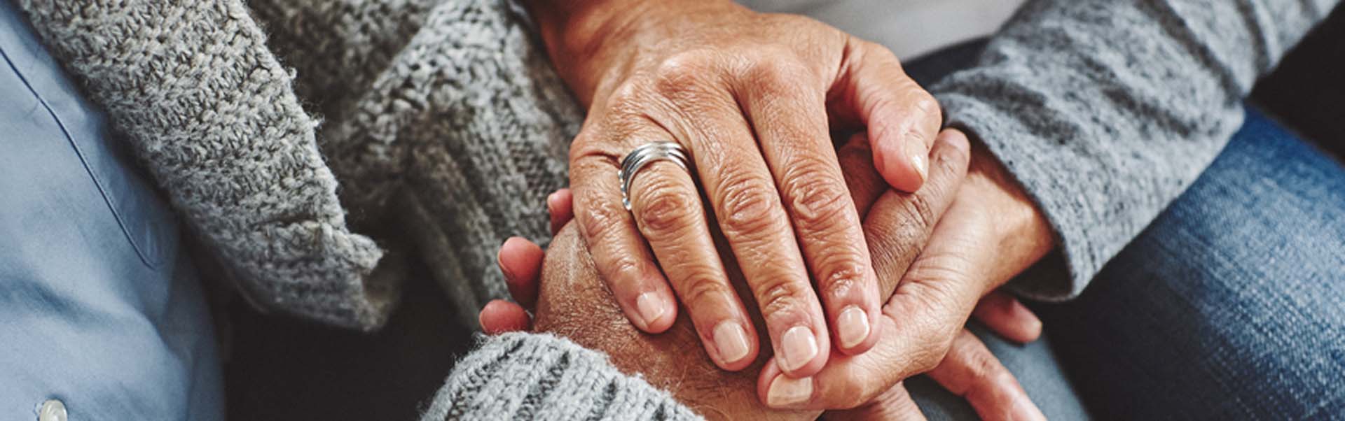 Female carer holding hands of senior man