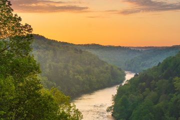 Golden light washes across the scene of a river through the Appalachian mountains