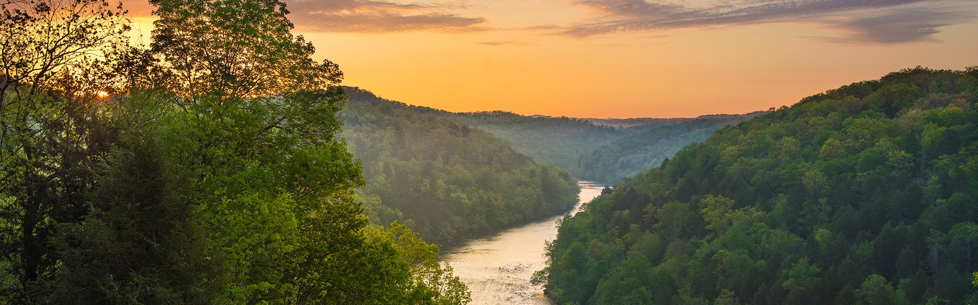 Golden light washes across the scene of a river through the Appalachian mountains