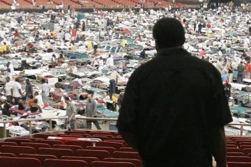 Crowds in a stadium with cots.