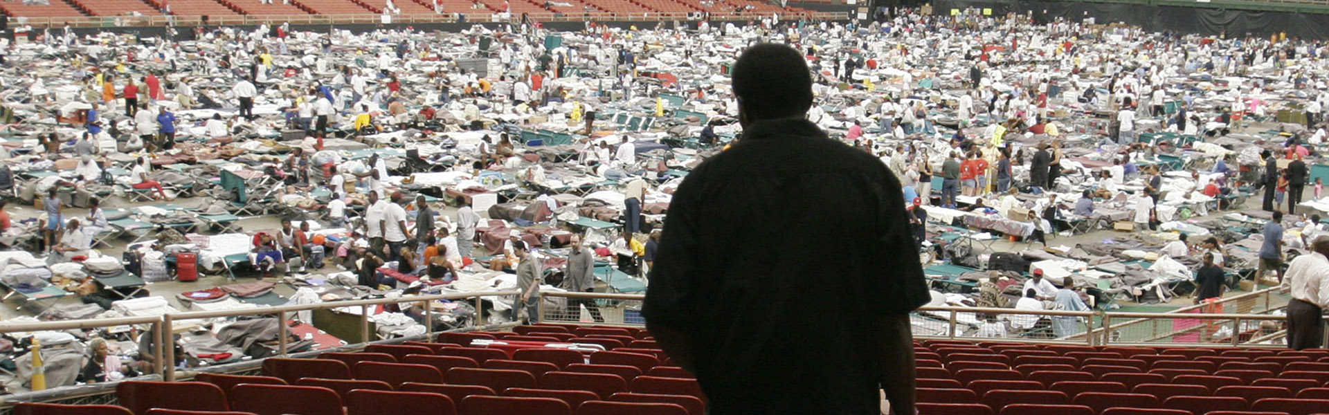 Crowds in a stadium with cots.