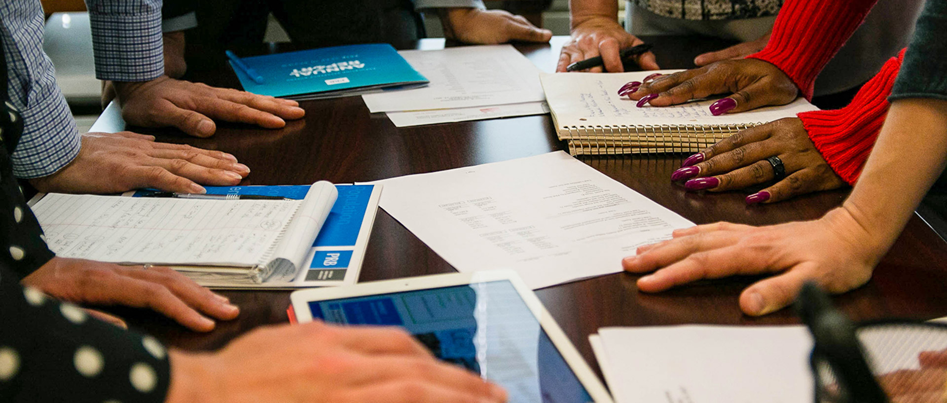 Desk with papers, notebooks and hands. hands