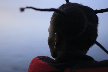 Woman with braids looks into a blue gray sky