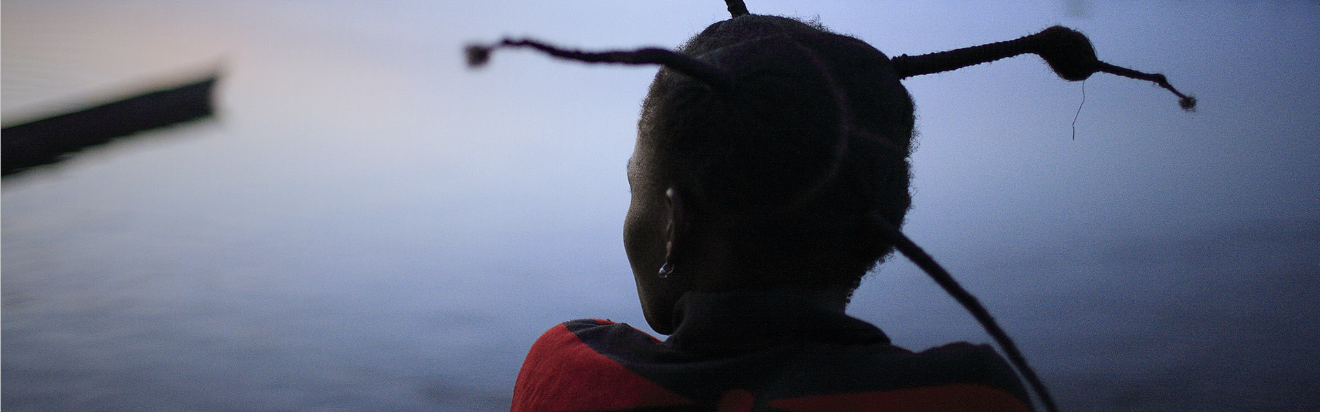 Woman with braids looks into a blue gray sky