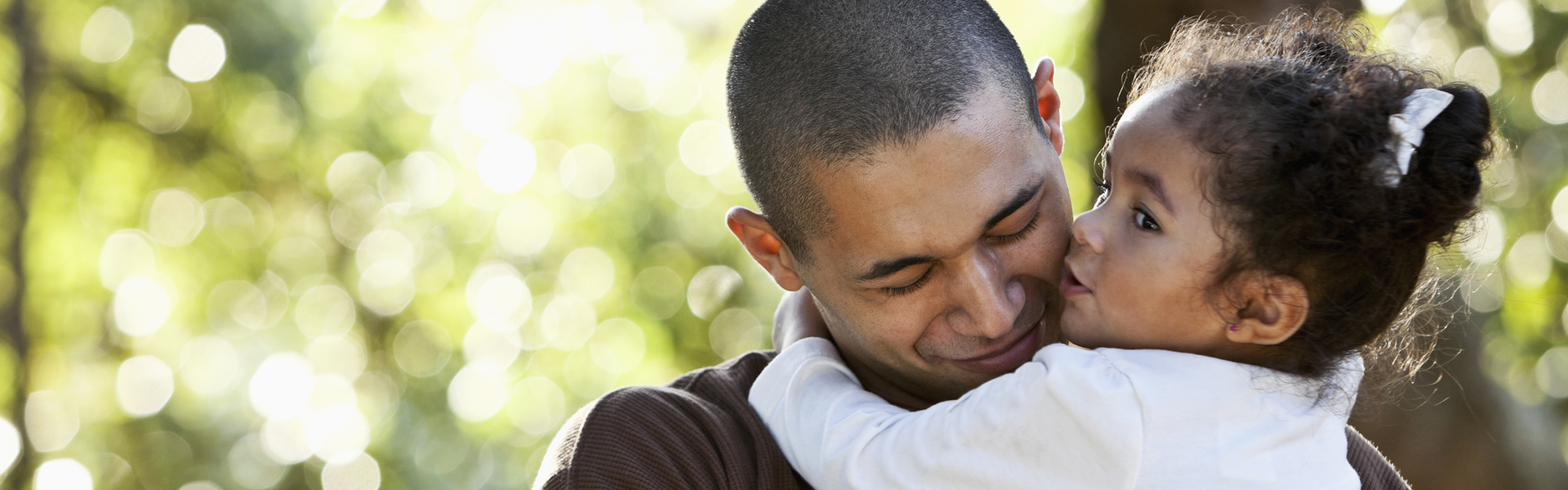 Hispanic father and daughter hugging at park