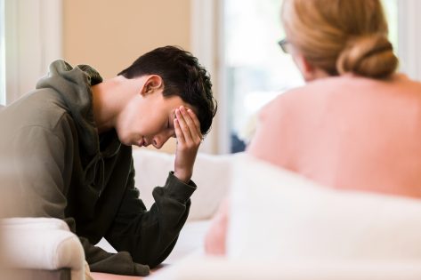 Teen boy puts head in hand as mother lectures