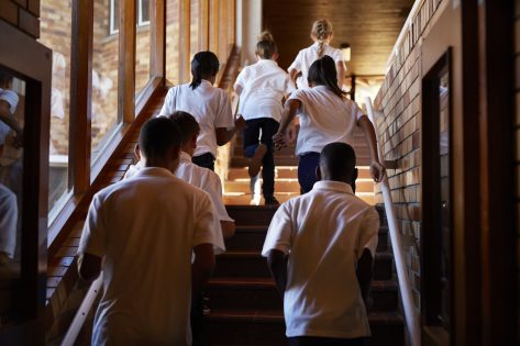 Young students running up stairs at the school