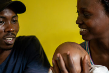 Black family with baby sitting on sofa