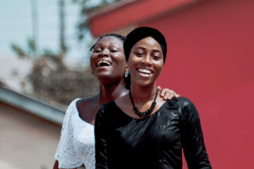 Portrait Of Smiling Friends With Arm Around In City