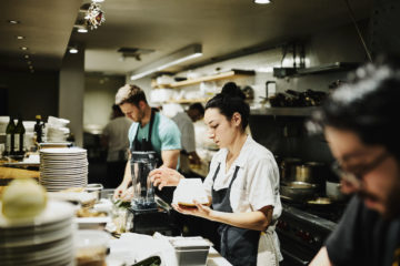 Female chef working with block of Parmesan cheese while preparing for dinner service in restaurant kitchen