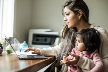 Mother multi-tasking with infant daughter in home office