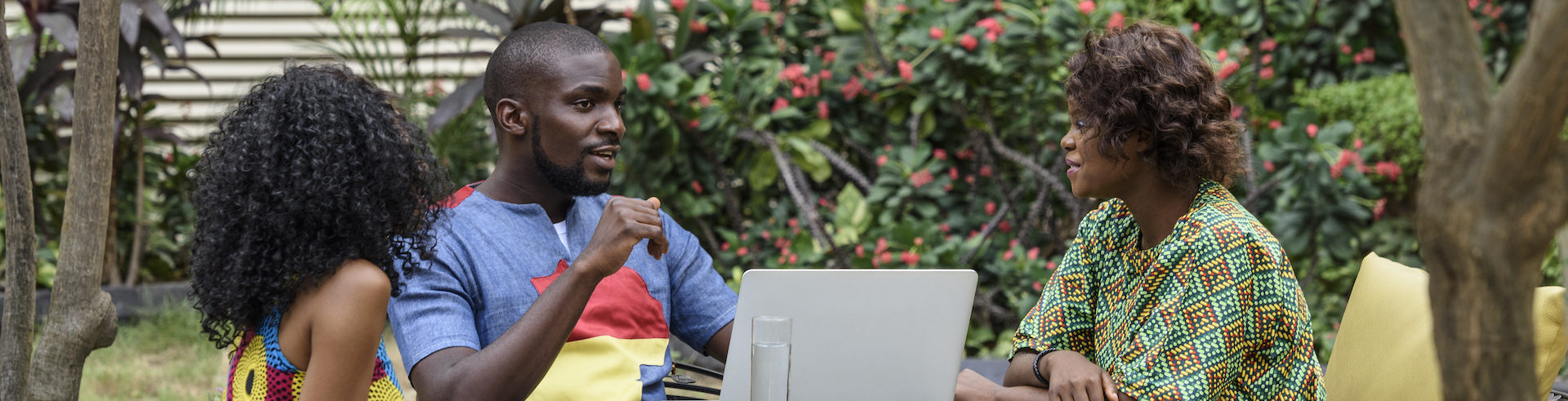 Nigerian colleagues with laptop talking in garden