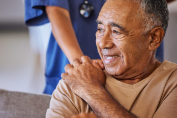 Nurse or doctor give man support during recovery or loss. Caregiver holding hand of her sad senior patient and showing kindness while doing a checkup at a retirement, old age home or hospital