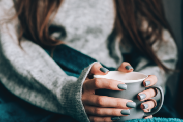 Shot of a young woman's hands wrapped around a mug.