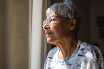 An elderly woman looks out a window