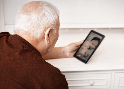 Senior man having video chat with his daughter and granddaughter on tablet computer