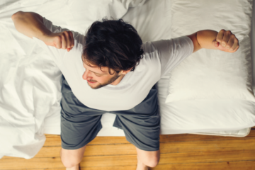 A young man stretches as he gets out of bed.