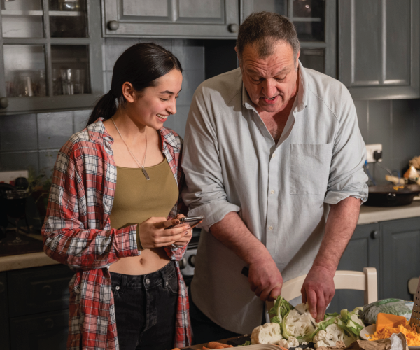 A stepfather and stepdaughter cook together.